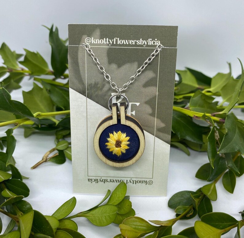 Hand stitched yellow sunflower on a navy blue background. handmade necklace pendant