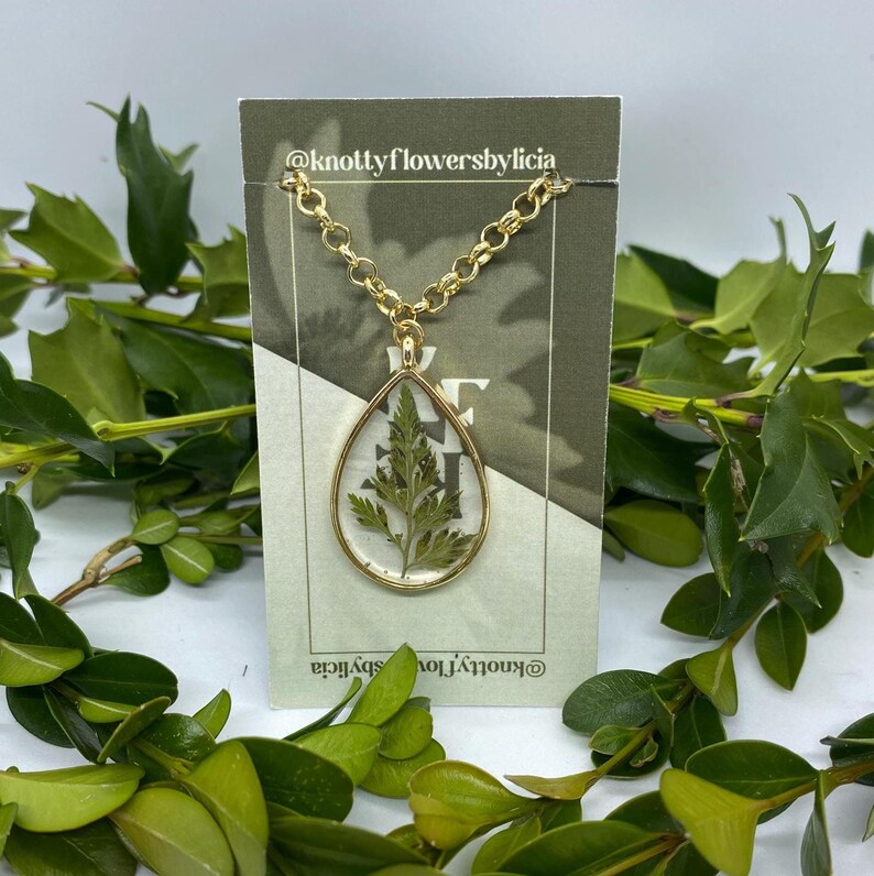 handmade resin necklace with a fern leaf as the centerpiece of the gold teardrop shaped pendant
