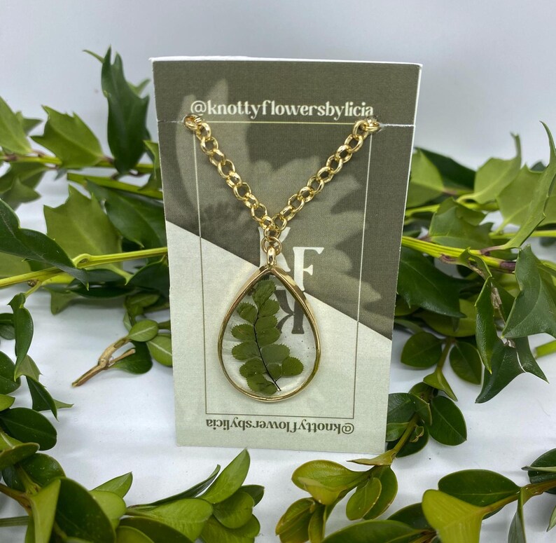 handmade resin necklace with a fern leaf as the centerpiece of the gold teardrop shaped pendant